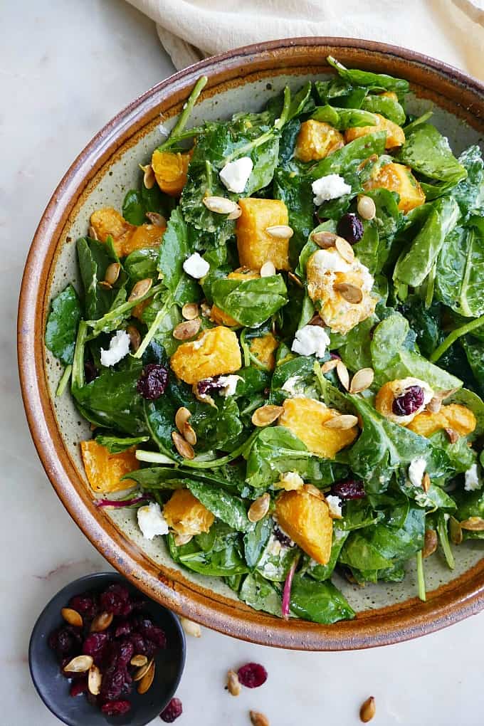 close up of roasted pumpkin salad in a large bowl on a white countertop