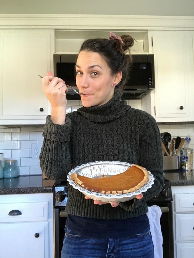 woman eating a forkful of carrot pie in a kitchen