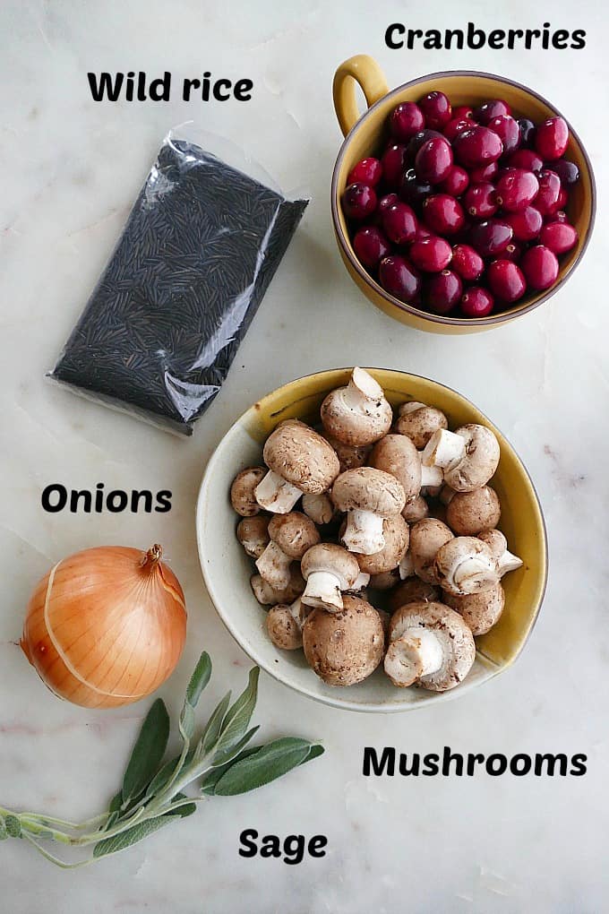 ingredients for mushroom cranberry wild rice pilaf labeled on a white counterop