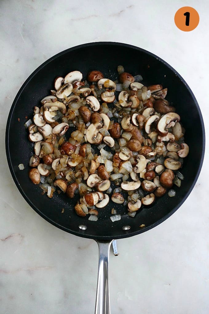sauteed mushrooms and onion in a black skillet on a white countertop
