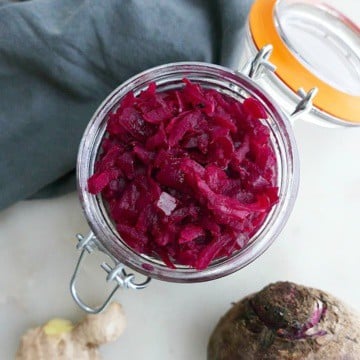close up of homemade beetroot relish in a glass jar next to a blue napkin