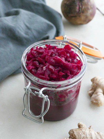 side view of beetroot relish in a glass jar with a blue napkin behind it
