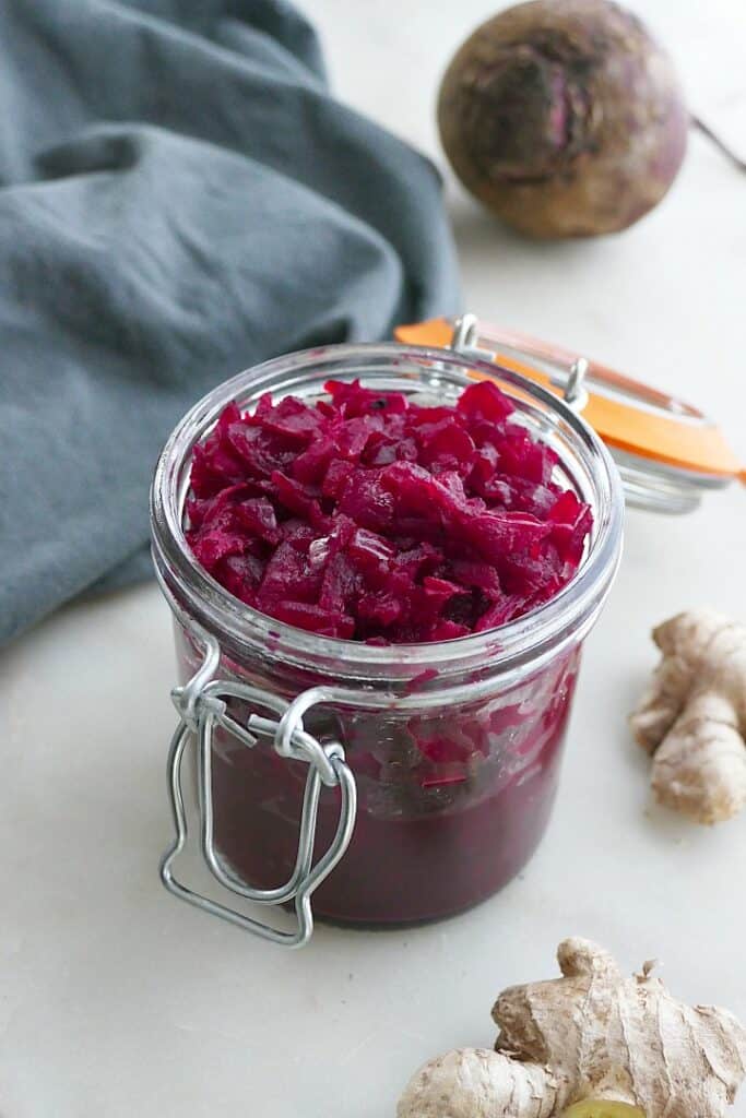 side view of beetroot relish in a glass jar with a blue napkin behind it