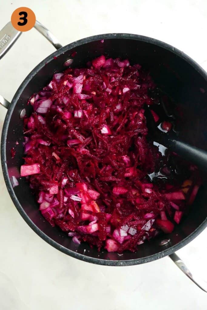 ingredients for beetroot relish in a large black pot with a black spoon