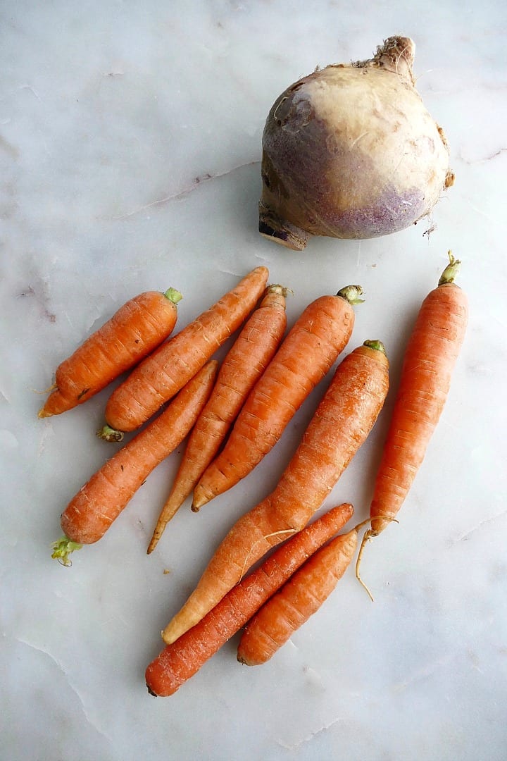 11 carrots and 1 rutabaga next to each other on a white countertop