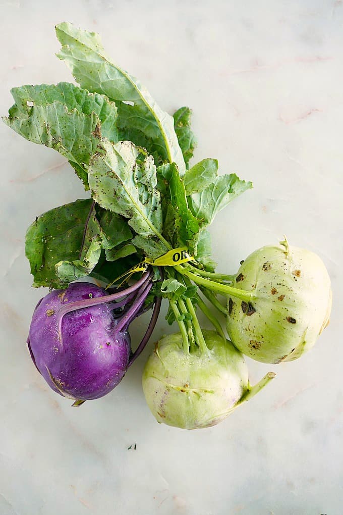 a bunch of purple and green kohlrabi tied at the top on a white counter