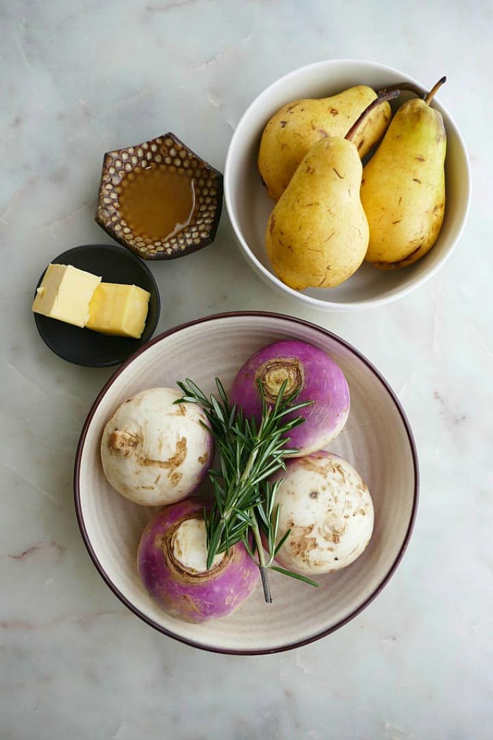 counter with bowls of pears, turnips and rosemary, honey, and butter