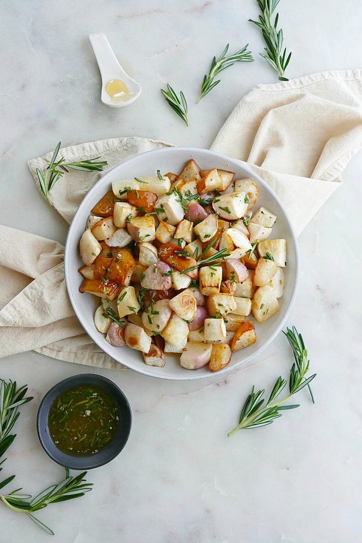 white plate on yellow napkin with roasted turnips and pears with rosemary on the counter