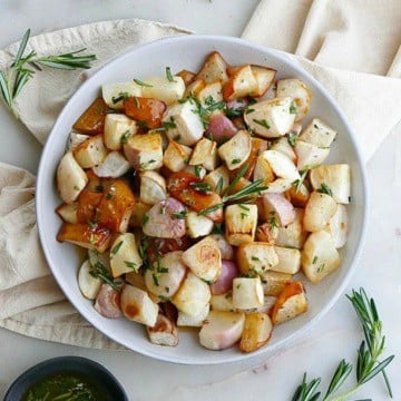 close up of roasted turnips and pears on white plate on top of a yellow napkin