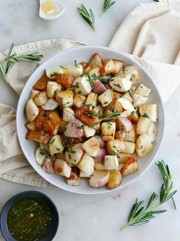 close up of roasted turnips and pears on white plate on top of a yellow napkin