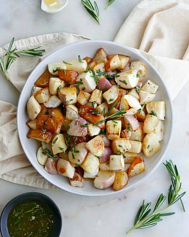 close up of roasted turnips and pears on white plate on top of a yellow napkin