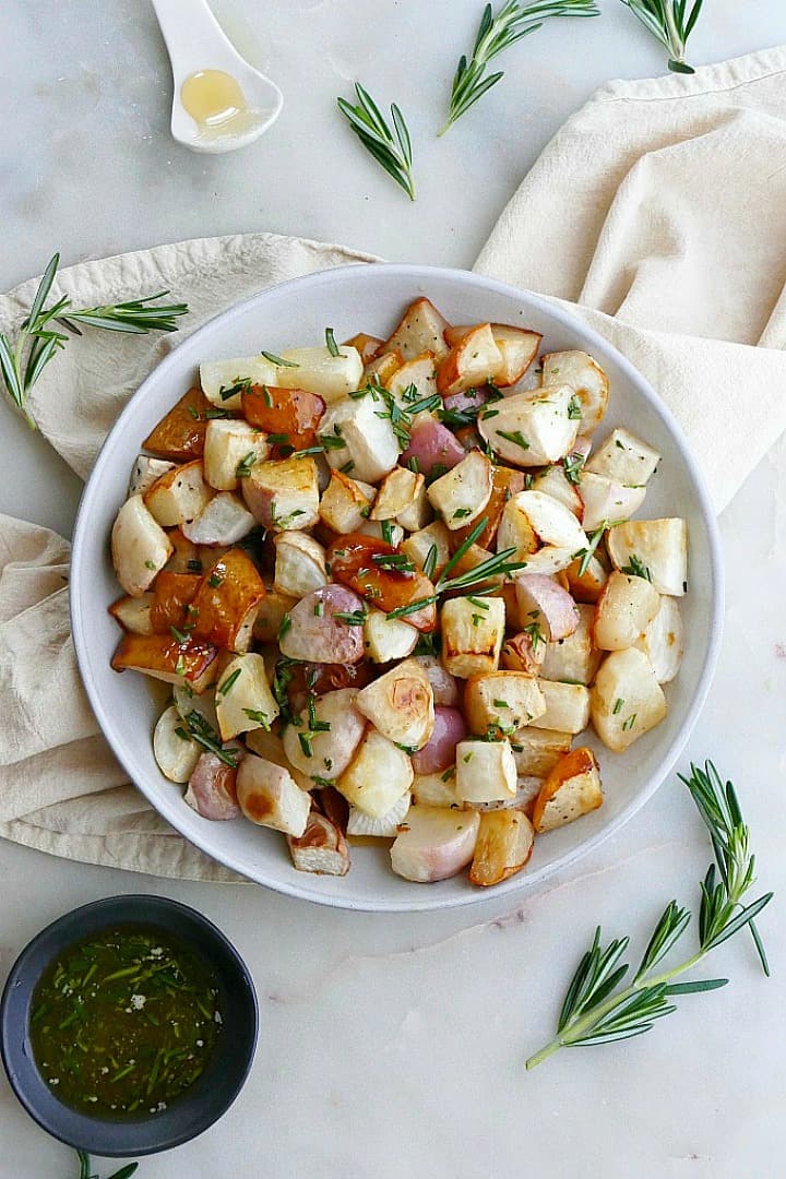 close up of roasted turnips and pears on white plate on top of a yellow napkin