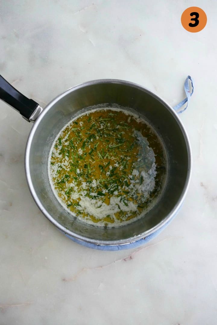 small saucepan with rosemary, honey, and butter on white counter