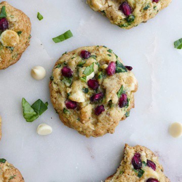 close up of one white chocolate chip spinach cookie on a white counter around other cookies