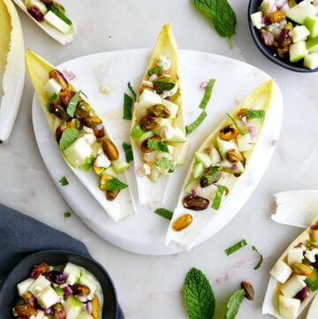 three stuffed endives on a small white marble plate on a counter