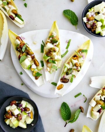 three stuffed endives on a small white marble plate on a counter