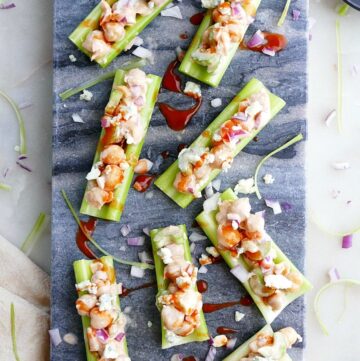 8 buffalo chickpea salad stuffed celery sticks on a blue marble board on a white counter