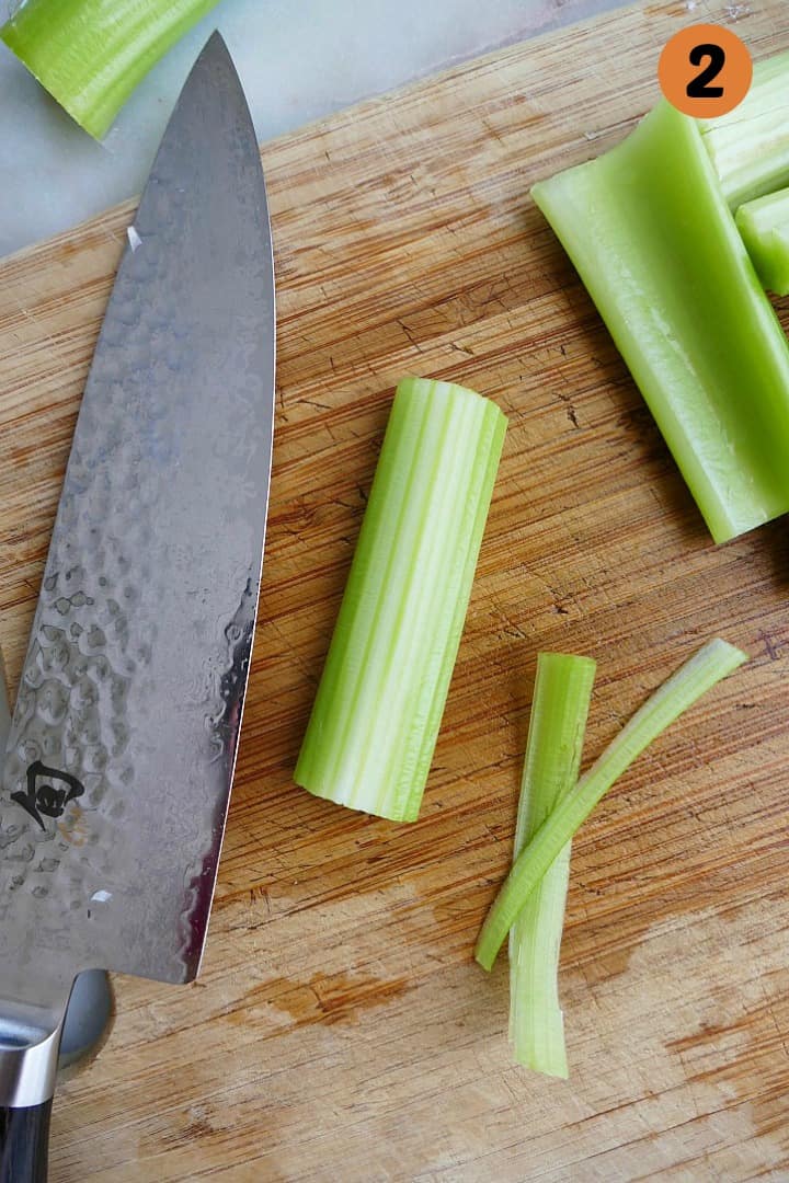 celery sticks on a bamboo cutting board next to a sharp chef's knife