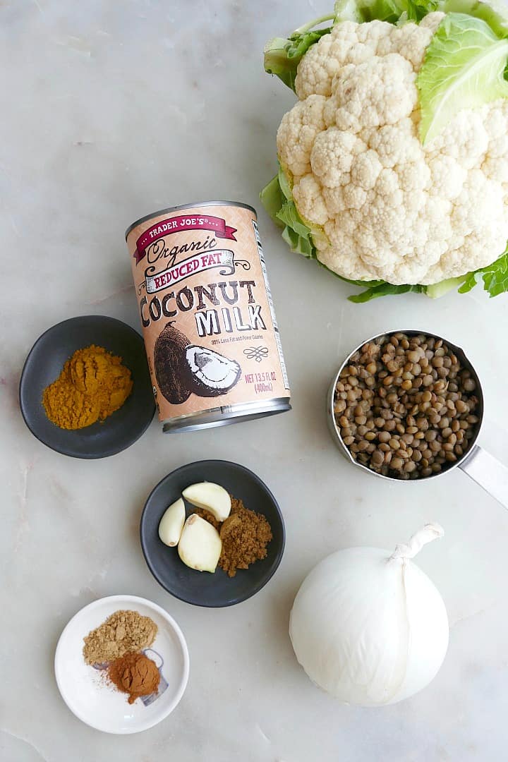 cauliflower, lentils, onion, coconut milk, and spices on a white counter