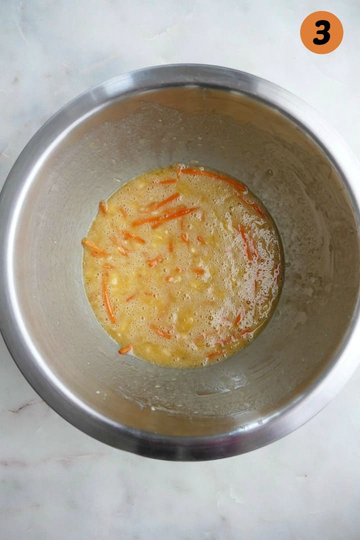 wet ingredients for carrot bread whisked together in a silver mixing bowl