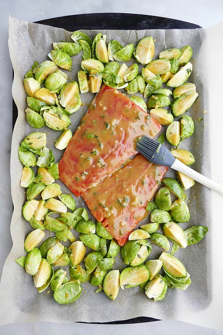 salmon and brussels sprouts coated in a maple mustard glaze on a lined baking sheet