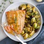maple mustard salmon and brussels sprouts on a white plate with a gold fork