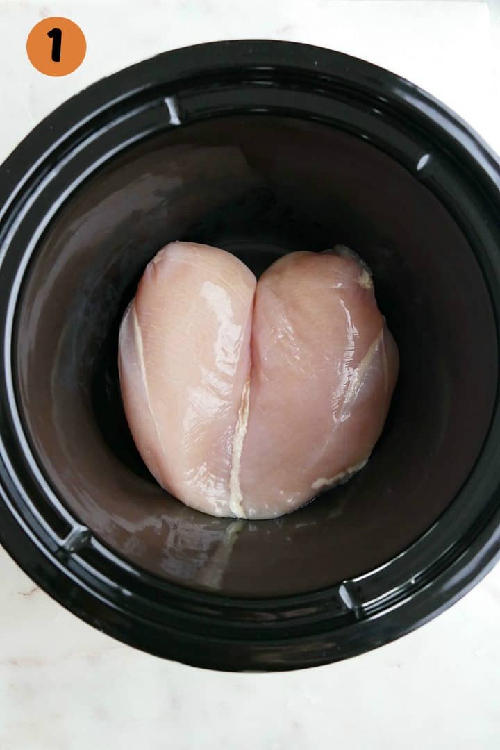 two chicken breasts in a crockpot on a white counter