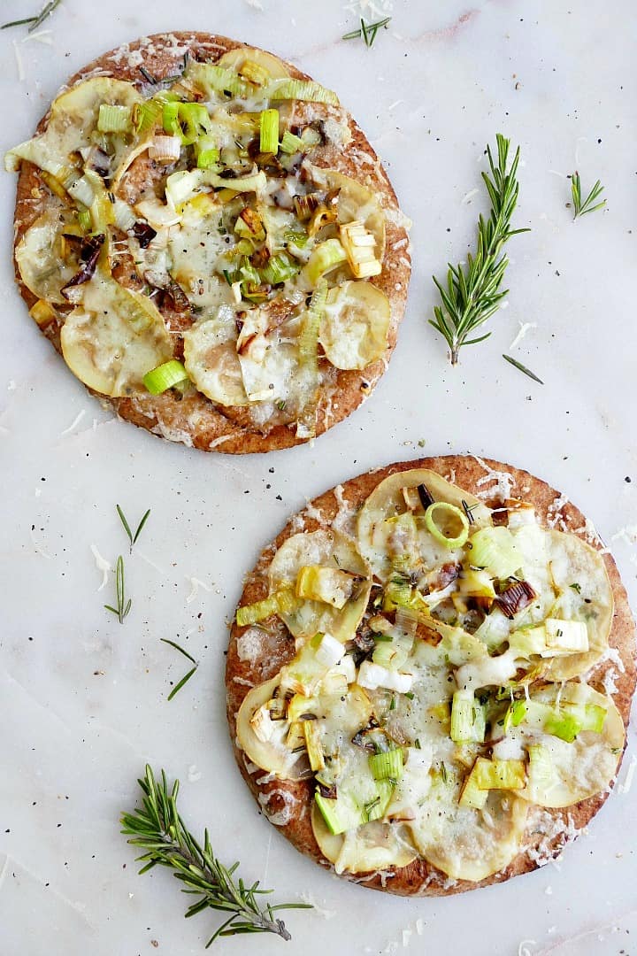 two individual potato leek pizzas on pita bread on a white counter