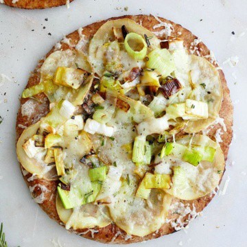 potato leek pizza on pita on a white counter with rosemary