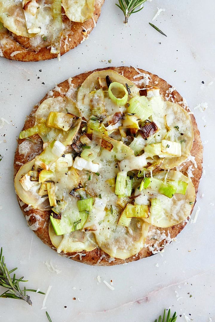 potato leek pizza on pita on a white counter with rosemary 