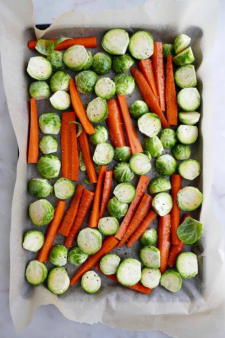 sliced brussels sprouts and carrots on a baking sheet lined with parchment paper