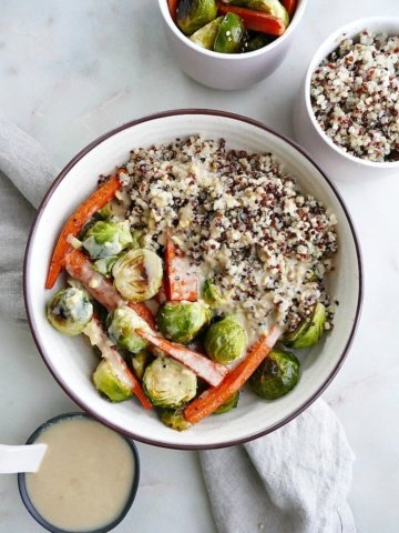 roasted vegetables with tri-colored quinoa and maple ginger tahini in a white bowl