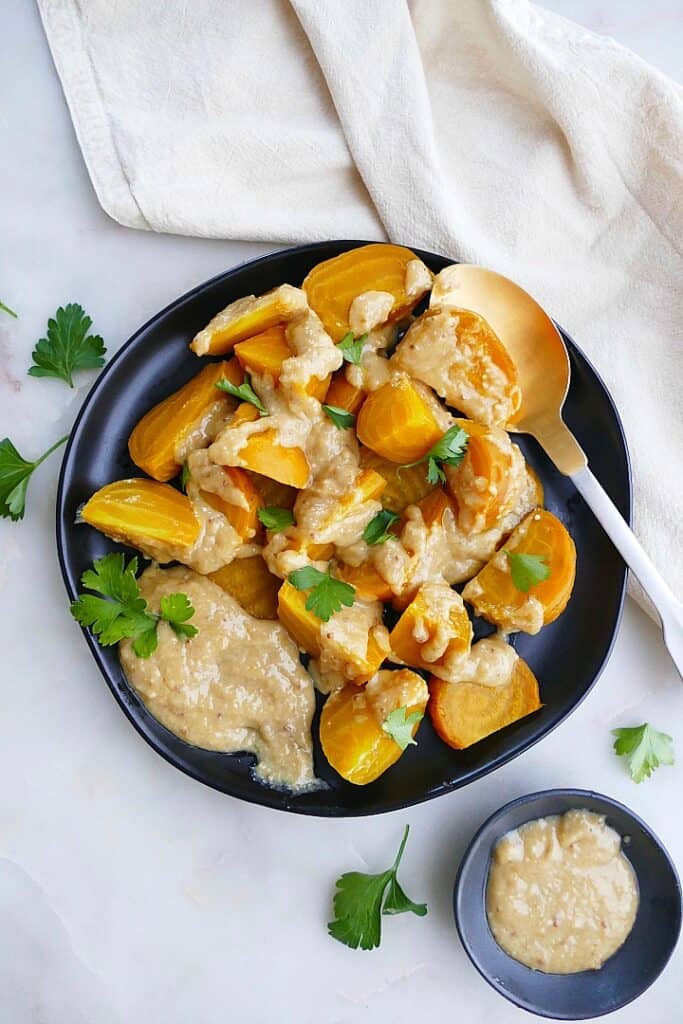 roasted golden beets on a black plate with miso maple sauce