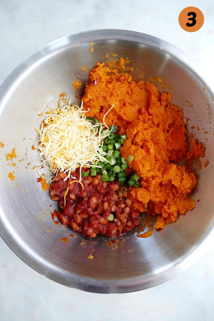 sweet potato flesh, cheese, scallions, and barbecue beans in a silver mixing bowl