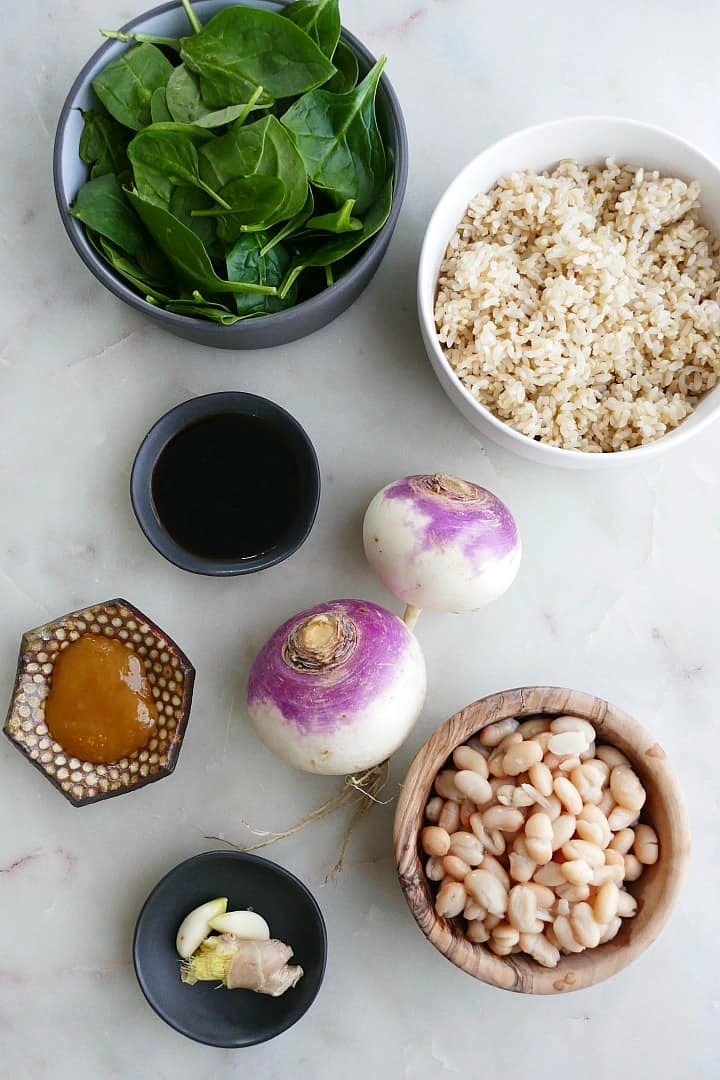 spinach, rice, turnips, beans, soy sauce, honey, garlic, and ginger in bowls on a counter