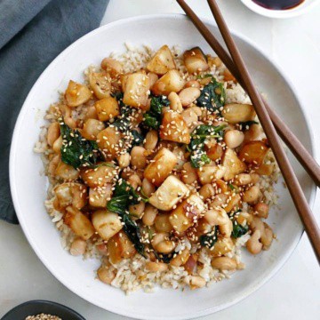 turnip stir fry on a white plate with brown chopsticks next to a blue napkin