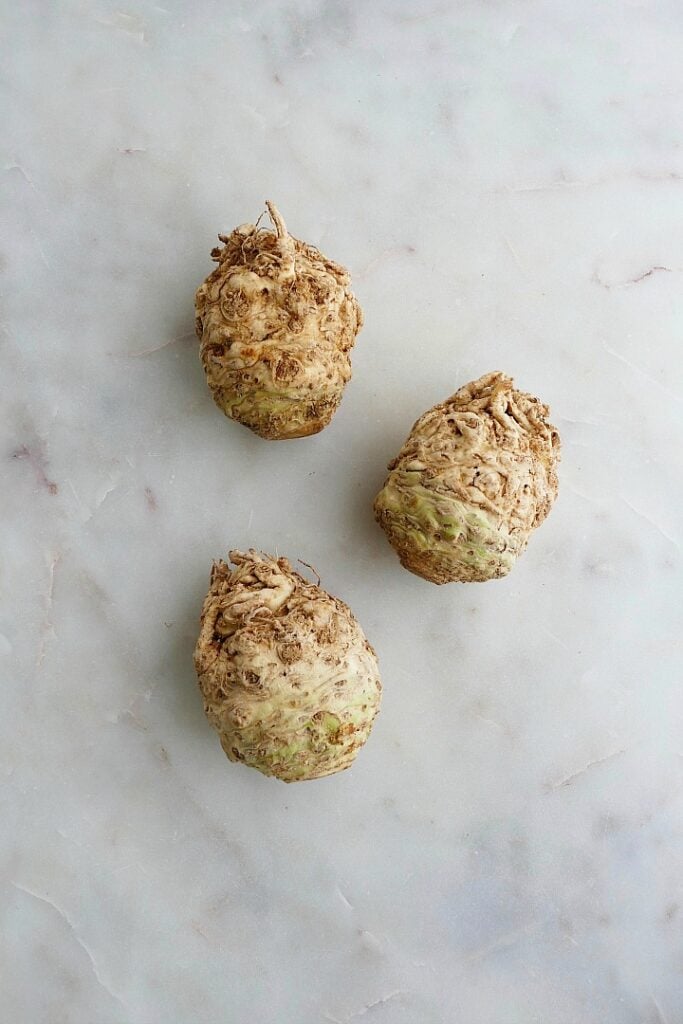 three knobs of celery root next to each other on a white counter