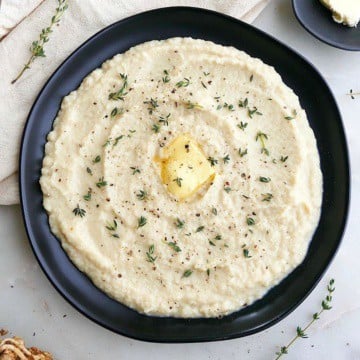 celeriac mash with a pat of butter and thyme leaves on a black plate