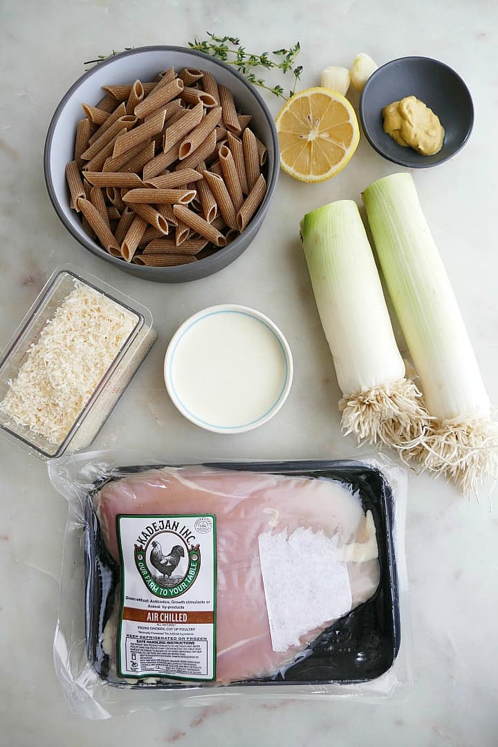 whole wheat pasta, parmesan cheese, cream, leeks, chicken, and lemon on a counter