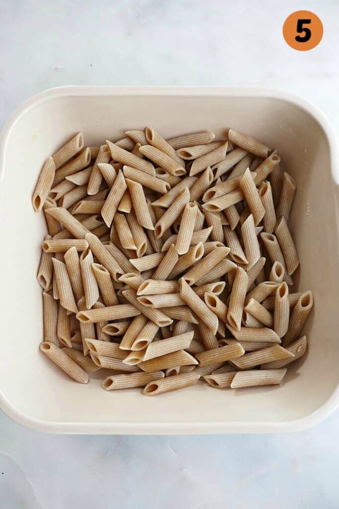 cooked whole wheat penne pasta in an 8x8 ceramic baking dish