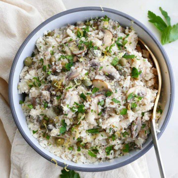 greek cauliflower rice in a blue and white bowl on a white counter