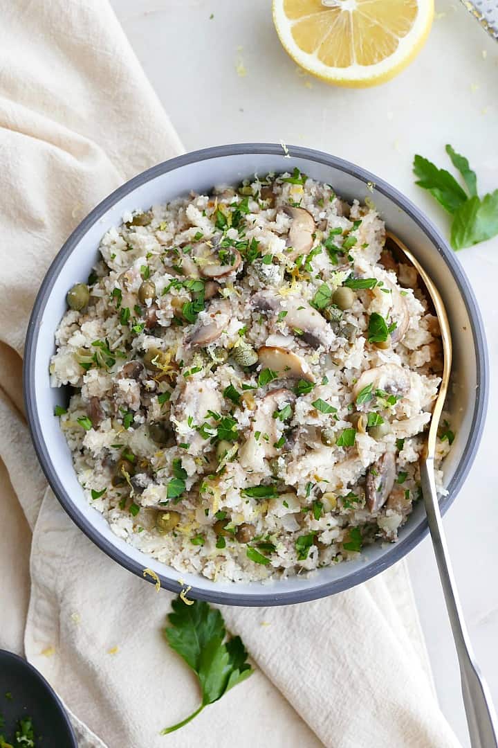 greek cauliflower rice in a blue and white bowl on a white counter