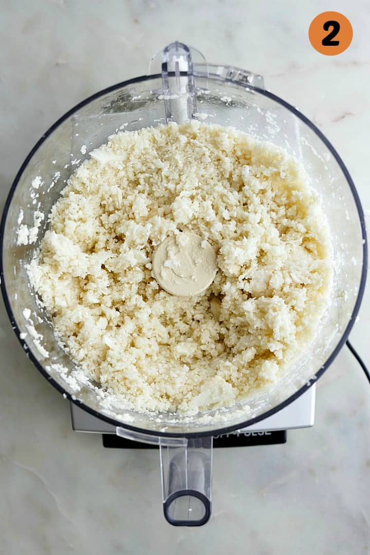 chopped cauliflower in a food processor with the number 2 in the top corner