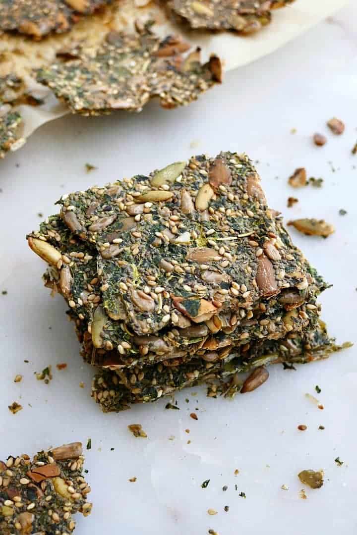 4 kale crackers stacked on top of each other on a white counter