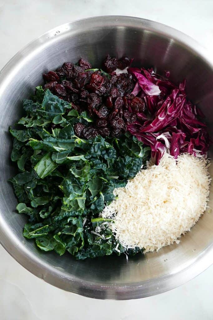 kale, radicchio, dried cherries, and parmesan cheese in a metal mixing bowl