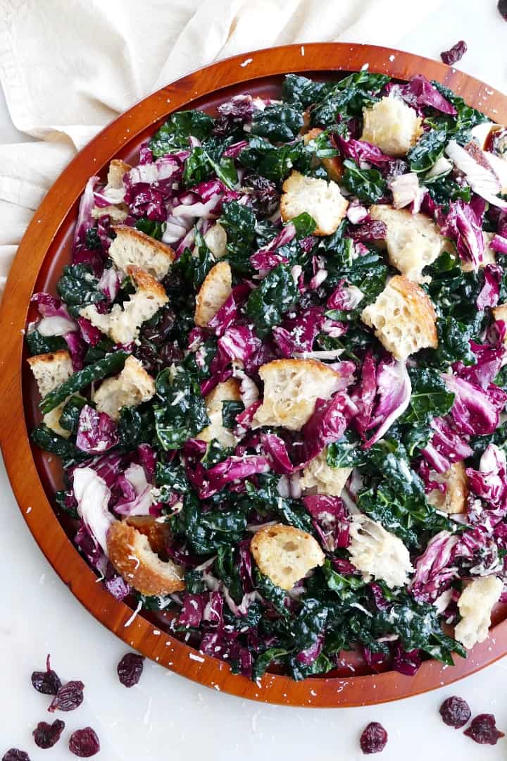 close up of kale radicchio salad with sourdough croutons on a large wooden platter