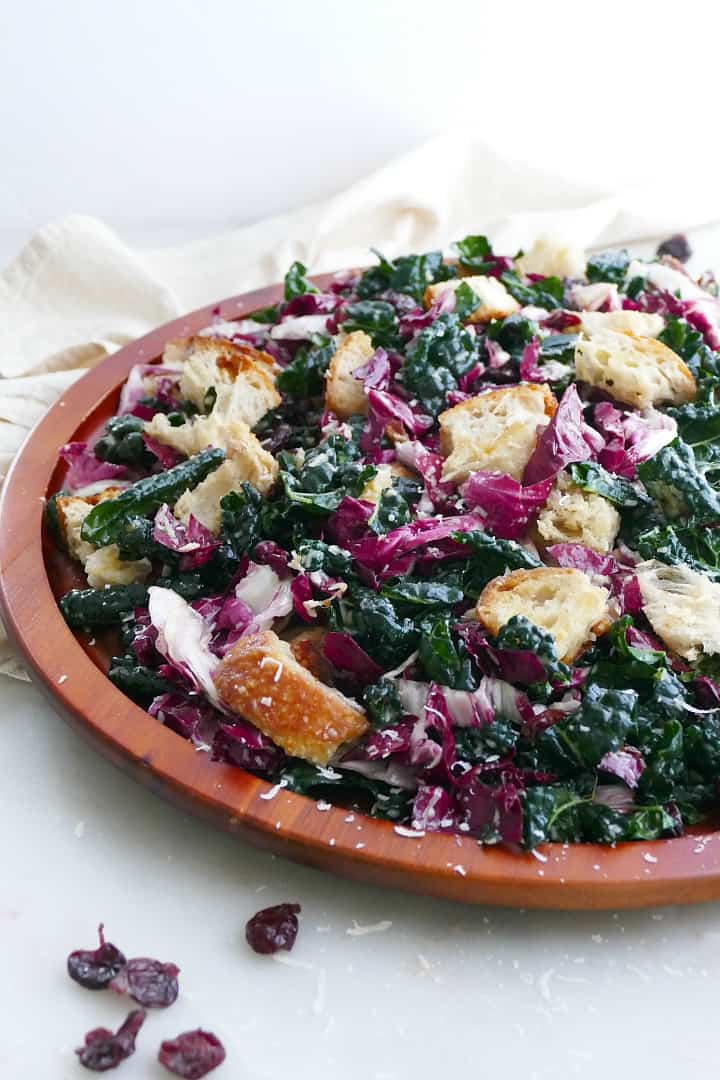 side view of kale radicchio salad and sourdough croutons on a wooden platter