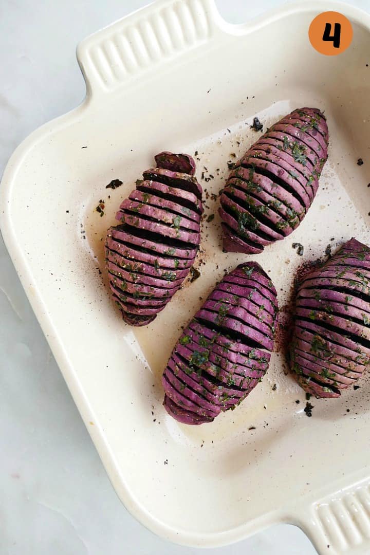 4 cooked hasselback purple sweet potatoes in a square dish on a counter
