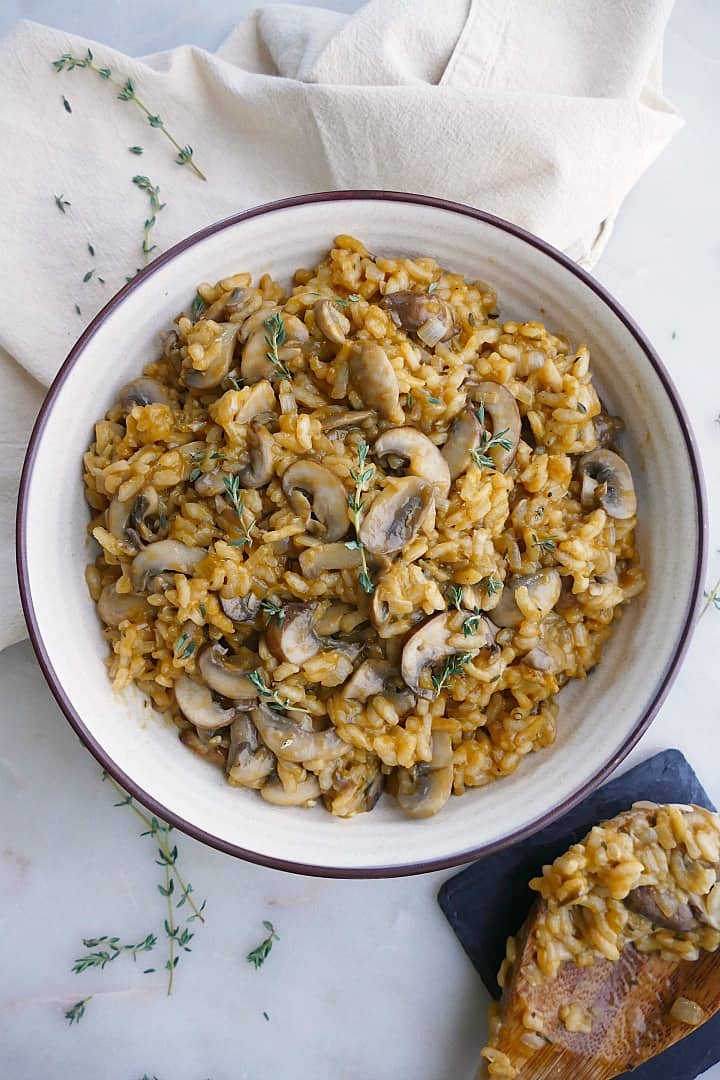 vegan mushroom risotto in a white bowl with thyme on a napkin 