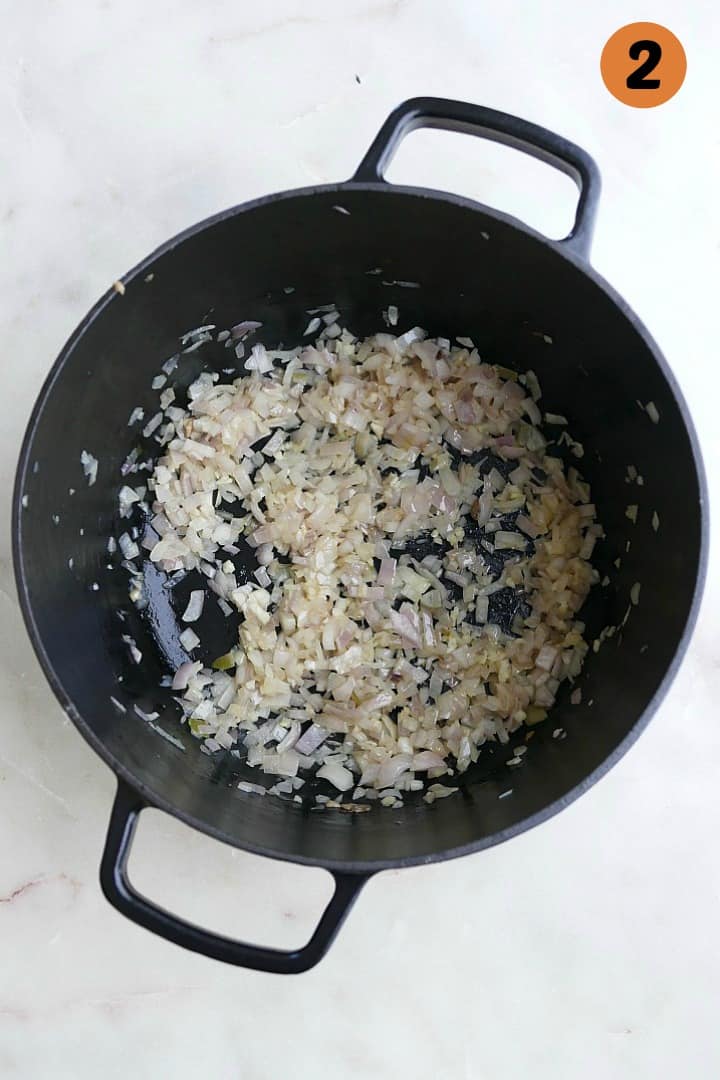 sauteed shallots in a black dutch oven on a white counter